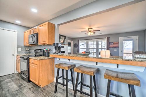 a kitchen with wooden cabinets and bar stools at Table Rock Lake Home - Fire Pit and Lake Views! in Golden