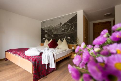 a hotel room with a bed with purple flowers at Hotel Rovanada Wellness & BergNatur in Vals