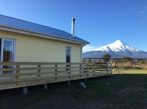 a house with a fence and a mountain in the background at OmShanti in Puerto Varas