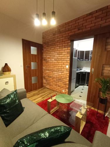 - un salon avec un canapé et un mur en briques dans l'établissement MK Apartament I, à Rzeszów
