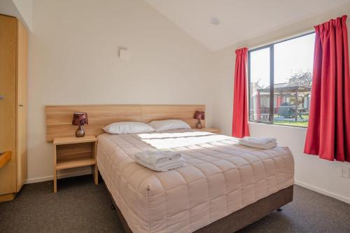 um quarto com uma cama grande e uma janela em Christchurch Park Motel em Christchurch