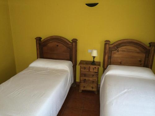 two beds in a room with yellow walls at Bekoabadene in Menaka