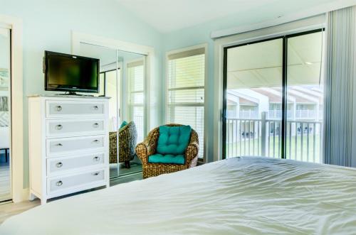 a bedroom with a bed and a tv and a chair at 2 C, Three Bedroom Townhome in Destin