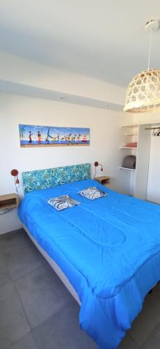 Una gran cama azul en una habitación blanca en Epic Playa unión, en Puerto Rawson