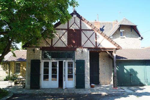 a house with white doors and a garage at Normand'Histoire Gite 1869 in Isigny-sur-Mer