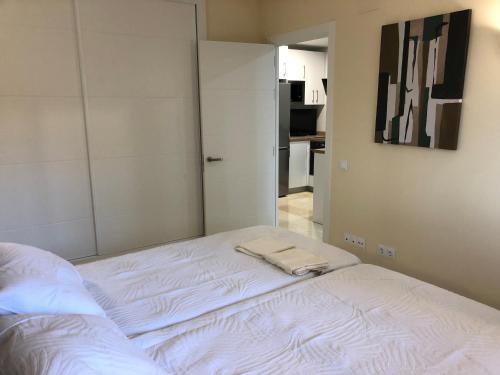 Una cama blanca con dos toallas en una habitación en Moderno Apartamento en Primera línea Paseo Marítimo Fuengirola, en Fuengirola