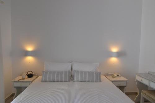 a bed with a white comforter and pillows on it at Artemis Hotel in Antiparos