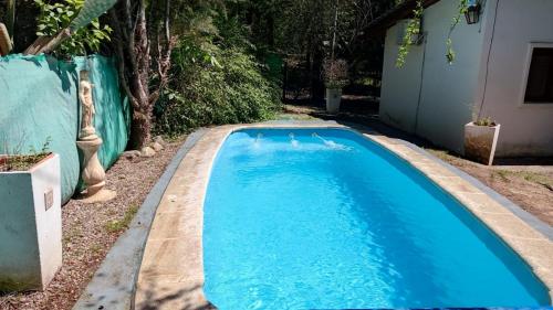 a blue swimming pool in a yard with a fence at Posada del Carruaje in Santa Rosa de Calamuchita