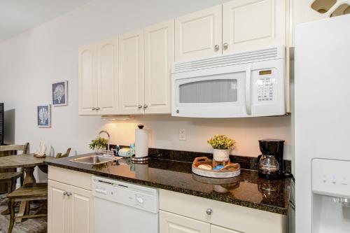 a kitchen with white cabinets and a sink and a microwave at Village of South Walton CB 243 in Rosemary Beach