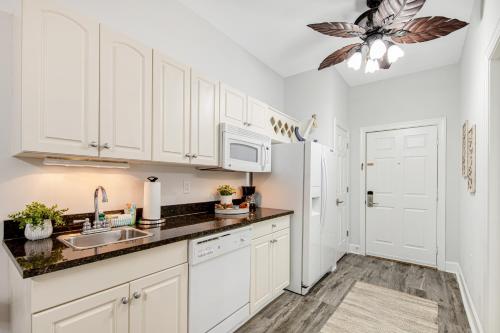 a kitchen with white cabinets and a sink and a refrigerator at Village of South Walton CB 243 in Rosemary Beach