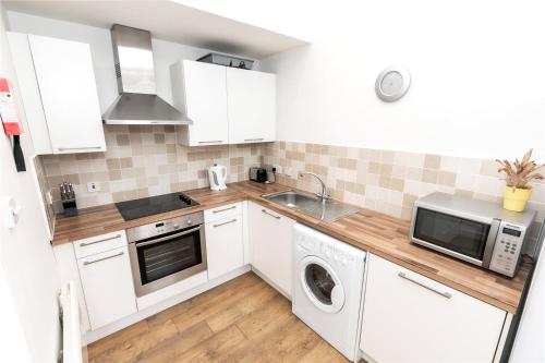 a kitchen with white cabinets and a washer and dryer at Top Stunning Relocation Aberdeen City Center Apartment in Aberdeen
