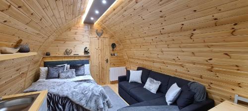 Loch Ewe Luxury Pods في Mellon Charles: غرفة بسرير واريكة في غرفة خشبية