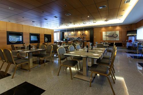 a dining room with tables and chairs in a restaurant at Sercotel Gran Fama in Almería