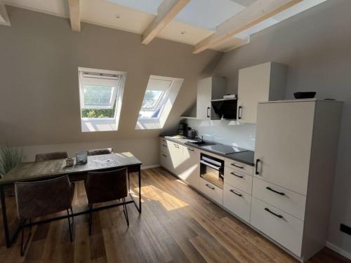 a kitchen with a table and a white refrigerator at 4Hafenzeiten - Ferienwohnung NIE 9 Lotte in Niendorf