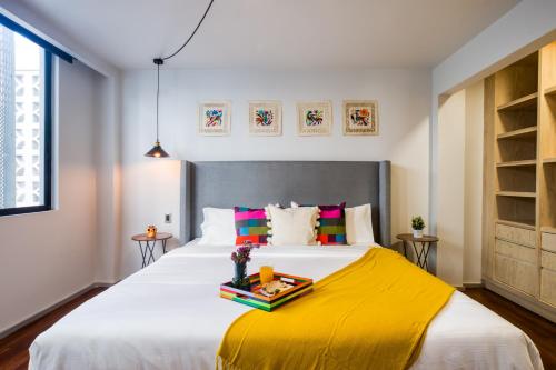 um quarto com uma cama grande e um cobertor amarelo em ULIV Condesa em Cidade do México