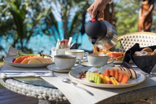 a table with plates of food and a person holding a tea pot at Mia Bacalar Luxury Resort & Spa in Bacalar