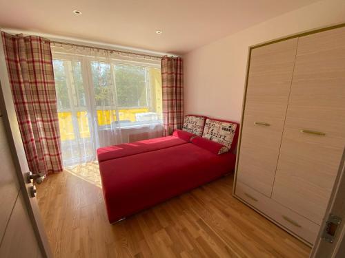 Sofá rojo en una habitación con ventana grande en Tomas Apartment, en Cēsis