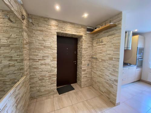 a stone wall in a kitchen with a black door at Tomas Apartment in Cēsis