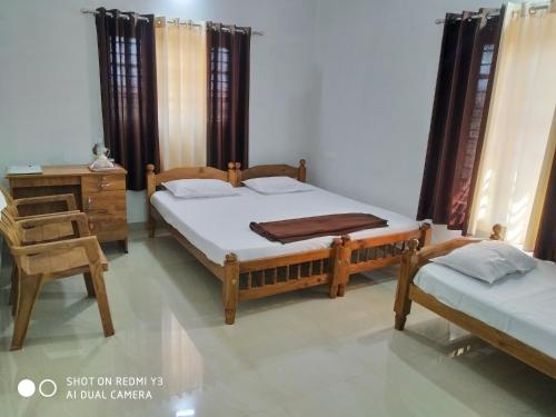 um quarto com 2 camas, uma secretária e uma cadeira em Ammu's home stay em Panamaram