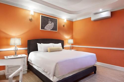 a bedroom with a large bed and orange walls at Hotel la Perla Leon in León