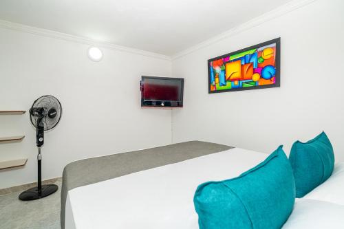 a bedroom with a bed with blue pillows and a tv at Ayenda Casa San Pablo in Medellín