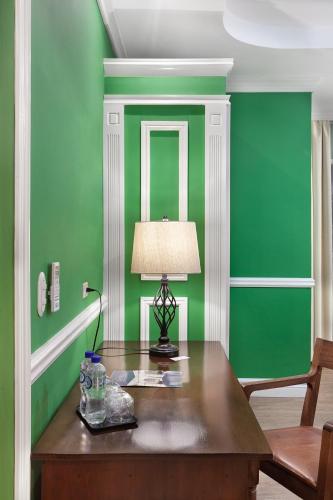 a green room with a table with a lamp on it at Hotel la Perla Leon in León