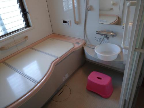 een kleine badkamer met een toilet en een roze kruk bij コウノトリの里の宿 in Fukiage