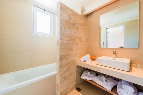 a bathroom with a sink and a tub and a mirror at Afandou Bay Resort Suites in Afantou