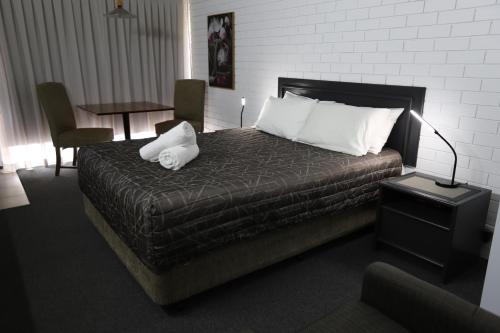 a bedroom with a bed with a lamp and a table at The Town House Motor Inn in Goondiwindi