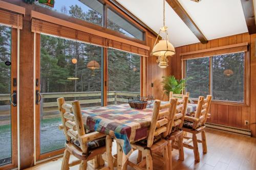 a dining room with a table and chairs and large windows at Catfish Lake Home in Eagle River