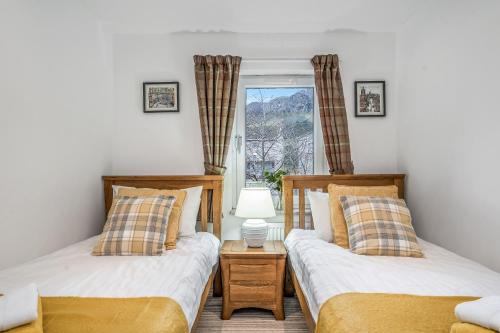 two twin beds in a room with a window at Spacious 3 Bedroom Modern House - Heart of Edinburgh - Private Main Door Entrance & Private Garden with Stunning Views of Arthur Seat in Edinburgh