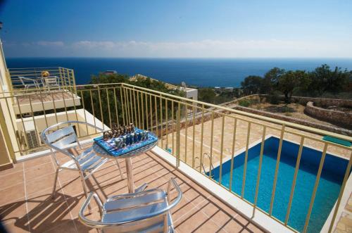 a balcony with a table and two chairs and a pool at Astra Villas in Skala Kefalonias