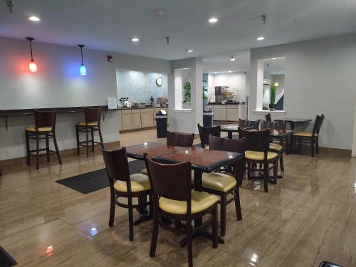 a dining room with tables and chairs and a kitchen at Hilltop Inn & Suites - North Stonington in North Stonington