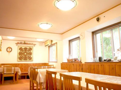 a dining room with tables and chairs and windows at Pension Buddy in Kitashiobara