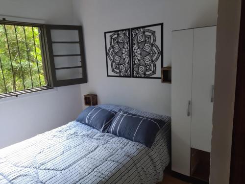 Un dormitorio con una cama con almohadas azules y una ventana en Arazá, en Cuchilla Alta