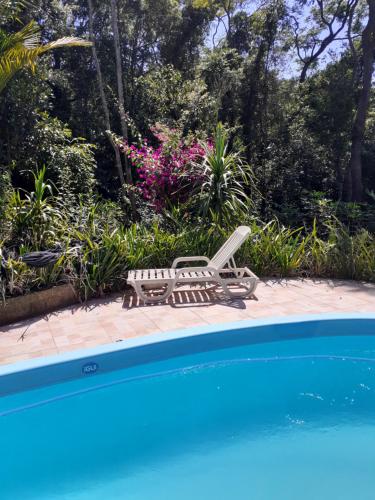 a pool with a chaise lounge and a table and a chair at Chácara Cantinho da Paz in Ibiúna