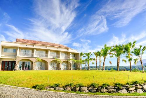 a house with palm trees in front of a field at Miinnon Village B&B in Meinong