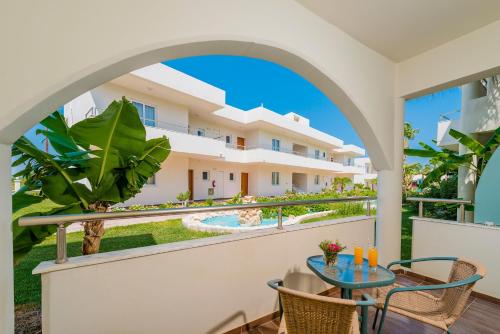 a balcony with a table and chairs and a building at Afandou Bay Resort Suites in Afantou