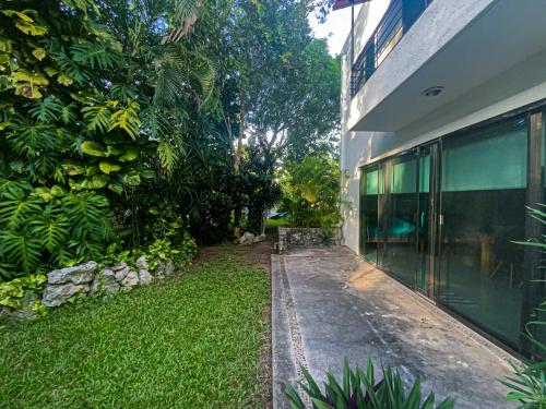 a building with a walkway next to a yard at Villa Selvática con Piscina en Playa del Carmen in Playa del Carmen