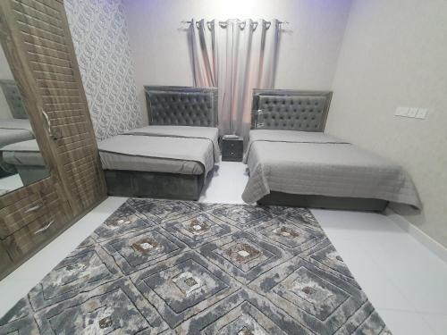 a bedroom with two beds and a rug on the floor at شاليه الشهد in Ma‘ābīlah