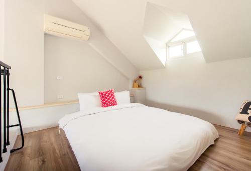 a bedroom with a white bed with a red pillow at Miinnon Village B&B in Meinong