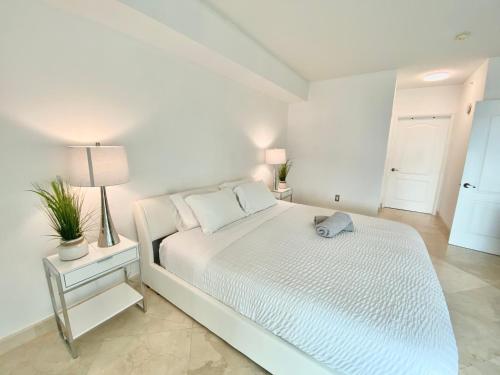 a white bedroom with a white bed and a lamp at The King David Condos in Miami Beach