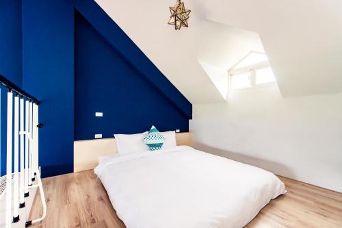 a bedroom with a blue wall and a white bed at Miinnon Village B&B in Meinong