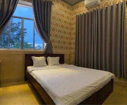 ein Schlafzimmer mit einem großen Bett mit Vorhängen und einem Fenster in der Unterkunft ĐÔNG NAM HOTEL CẦN THƠ in Cần Thơ