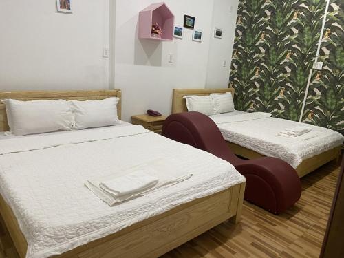 a room with two beds and a chair in it at Melody Homestay Quy Nhơn in Quy Nhon