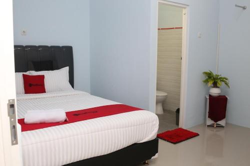 a bedroom with a large white bed with red pillows at RedDoorz Syariah near Suncity Mall Madiun in Madiun