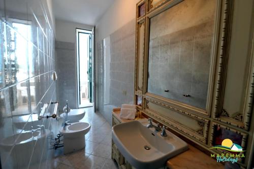a bathroom with a sink and a toilet and a mirror at Maremma Holidays-Casa Magò in Follonica