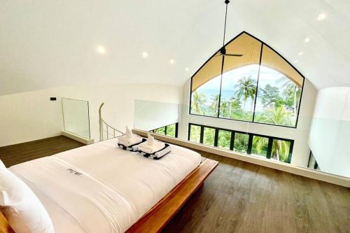 una grande camera da letto bianca con una grande finestra di Villa Oikos a Chaweng Noi Beach