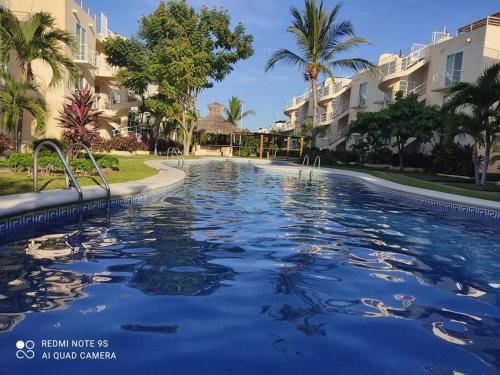 - une piscine dans un complexe avec des palmiers et des bâtiments dans l'établissement depto relajante Diamante, à Acapulco