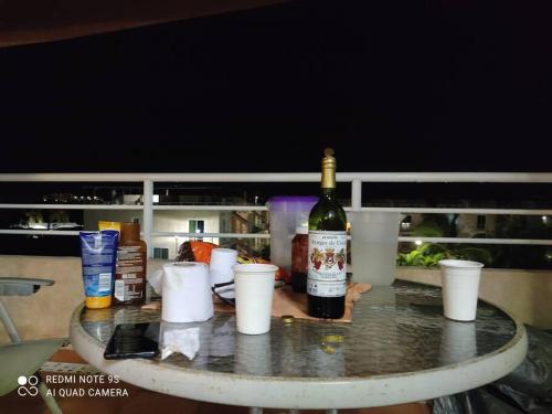 a bottle of wine sitting on a table with cups at depto relajante Diamante in Acapulco